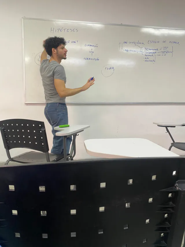 Rodolfo Oliveira conduzindo um treinamento em sala de aula diante de um quadro branco